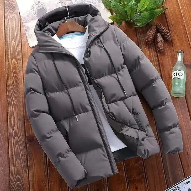Gray puffer jacket on a wooden surface with a bottle of Rioja wine and pine cones.