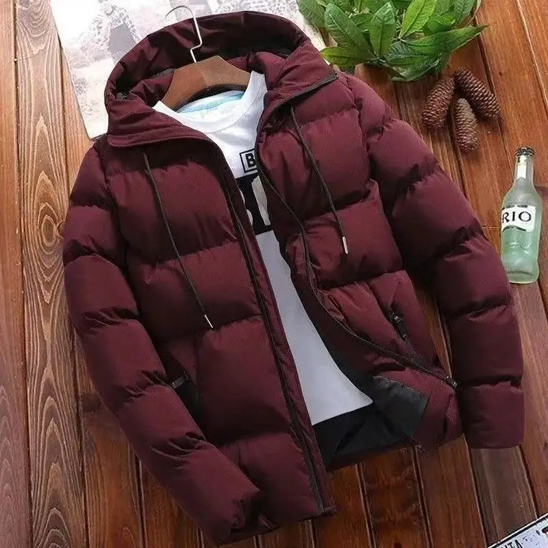 Maroon puffer jacket on a wooden surface with a bottle and plant in the background