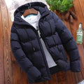 Navy blue puffer jacket on a wooden surface with a bottle and plant in the background